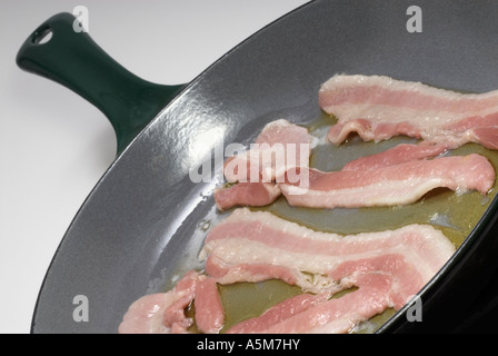 Streaky bacon rashers frying in a green 'cast iron' pan Stock Photo