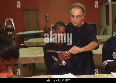 Teacher works with students in wood shop class at an inner city high school in Detroit Michigan Stock Photo
