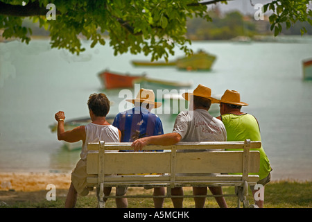 Hot day in Mauritius - Four men relaxing in the heat watching the fishing boats in the bay Stock Photo