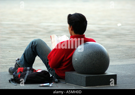 RAJ98782 People of Europe person reading a book resting against round shape Paris France Europe Stock Photo