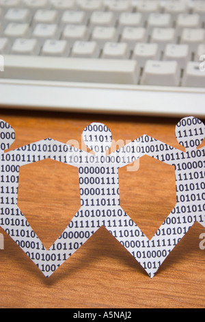 paper dolls with binary numbers on keyboard. symbolic of knowledge workers in the information technology industry Stock Photo