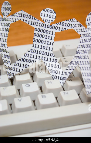 paper dolls with binary numbers on keyboard. symbolic of knowledge workers in the information technology industry Stock Photo