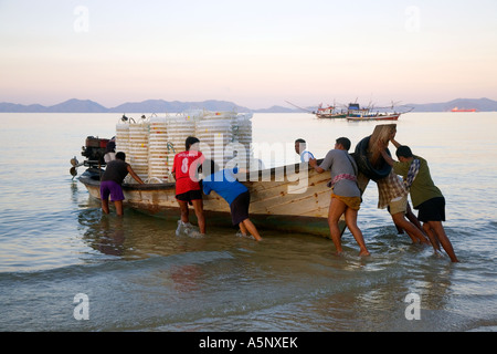 Fishing Boats, fishermen, seashore, workers, sea coast fishing, loaded boat, crew returning with catch at dawn Krabi Fishermans beach resort, Thailand Stock Photo