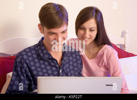 Young couple having fun while using their laptop from bed. Stock Photo