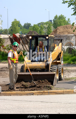 Construction workers using a bobcat mini tractor at a new development site in Michigan Stock Photo