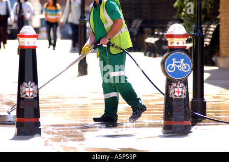 British council worker cleaning London street UK with pressure hose removing chewing gum from pavement Stock Photo