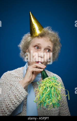 Older woman with noisemaker and party hat Stock Photo - Alamy