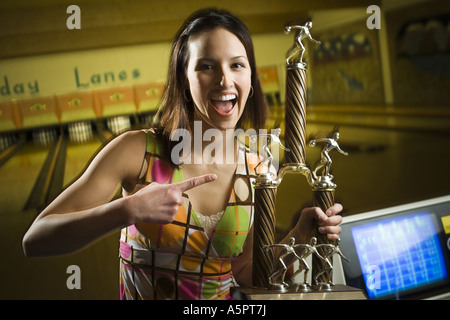 Portrait of a teenage girl holding a bowling trophy and laughing Stock Photo