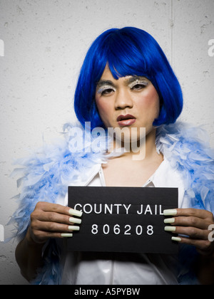 Mug shot of man in drag with blue wig and feather boa Stock Photo