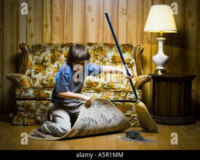 Boy sweeping dirt under rug Stock Photo - Alamy