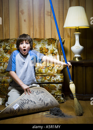 Boy sweeping dirt under rug Stock Photo - Alamy