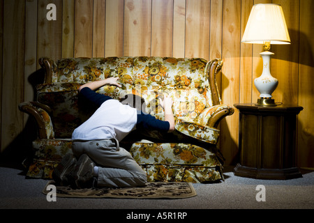 Boy searching under sofa cushions Stock Photo