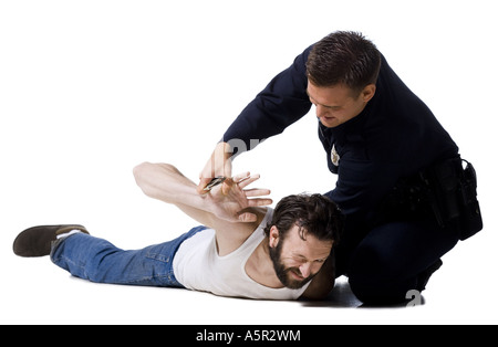 Police officer arresting man lying down with handcuffs Stock Photo
