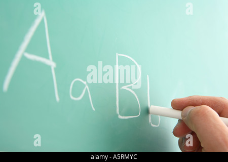 School teacher writing alphabet on chalkboard Stock Photo