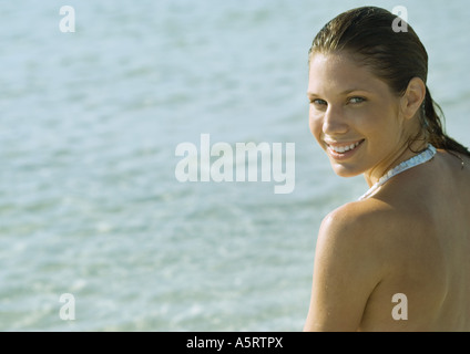 Young woman on beach, looking over shoulder at camera