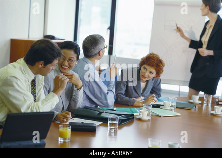 Colleagues at table talking to each other, laughing, during business presentation Stock Photo