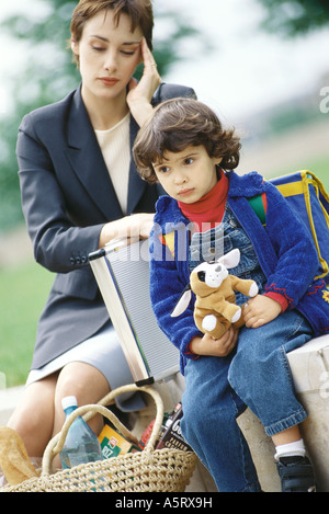 Businesswoman sitting with son, holding head Stock Photo