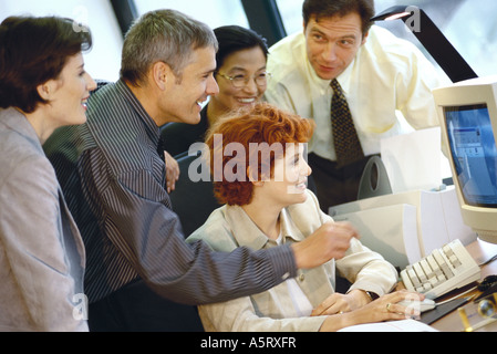 Business associates grouped around computer Stock Photo