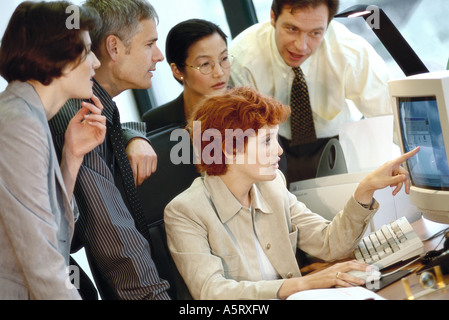 Business associates grouped around computer Stock Photo