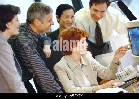 Business associates grouped around computer Stock Photo