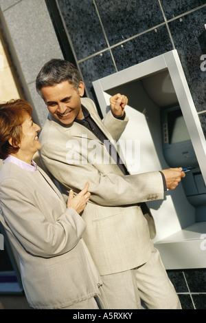 Mature couple standing at ATM machine Stock Photo
