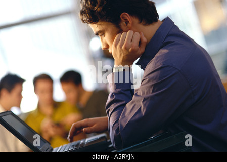 Young man using laptop, side view Stock Photo