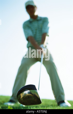 Golfer holding golf club, focus on club in foreground, low angle view Stock Photo