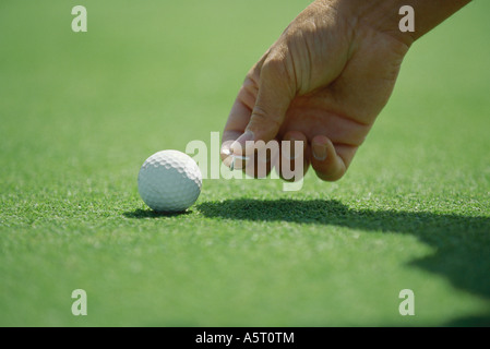 Golfer placing golf ball marker on turf, close-up of hand Stock Photo