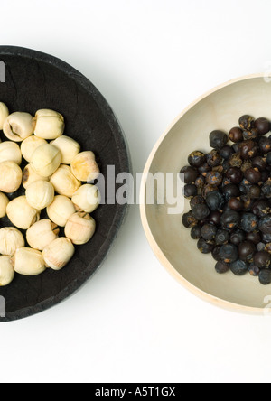 Two bowls, one containing lotus seeds, one containing dried juniper berries Stock Photo