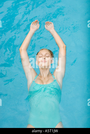 Young woman floating on back in pool, eyes shut Stock Photo