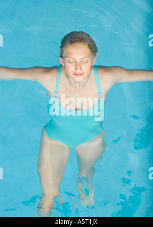 Young woman floating on back in pool, eyes shut Stock Photo