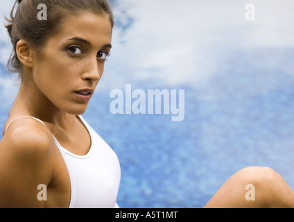Young woman sitting by edge of pool Stock Photo