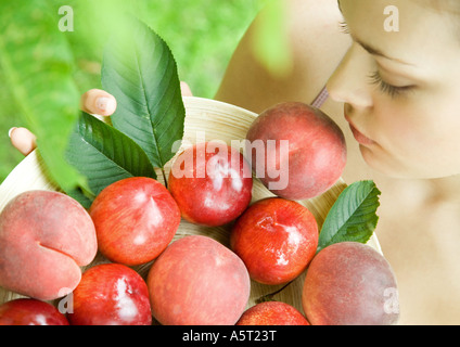 Woman holding bowl of peaches and nectarines
