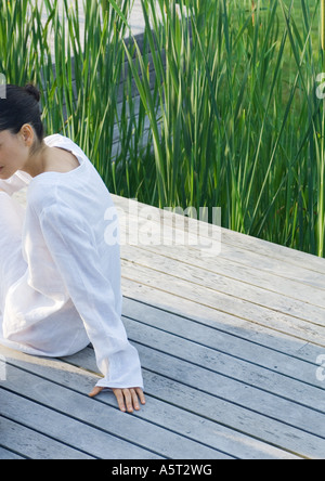 Woman sitting on deck, partial view Stock Photo