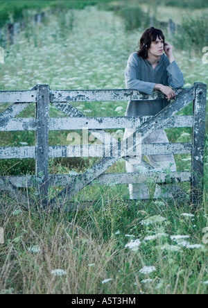 Man leaning on wooden fence, listening to headphones Stock Photo