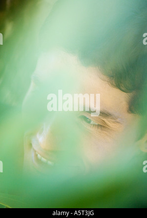 Man's face seen through blurred vegetation, close-up Stock Photo