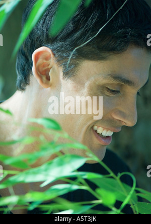 Man smiling, close-up of head, leaves in foreground Stock Photo