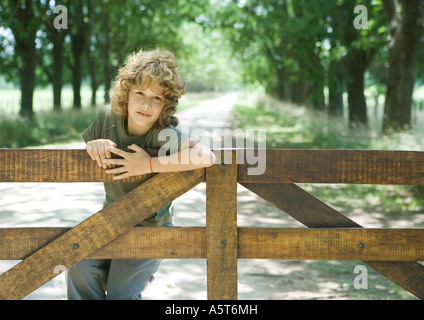 Boy hanging on fence Stock Photo