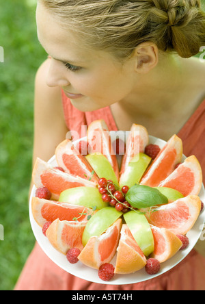 Woman holding plate full of fruit slices, high angle view Stock Photo