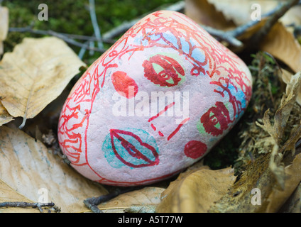 Stone decorated with face, lying on ground Stock Photo