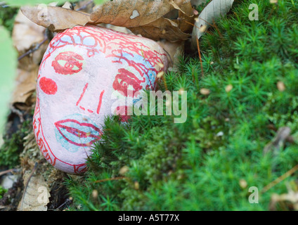 Stone decorated with face, lying on ground Stock Photo