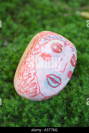 Stone decorated with face, lying on ground Stock Photo