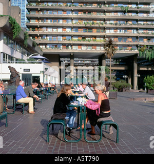People sitting at tables eating and drinking at the outdoor cafe on the lakeside terrace in summer at the Barbican Centre London UK    KATHY DEWITT Stock Photo
