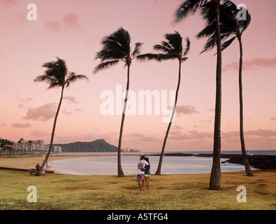 Couple on Magic Island at sunset with Waikiki Beach and Diamond Head beyond Stock Photo