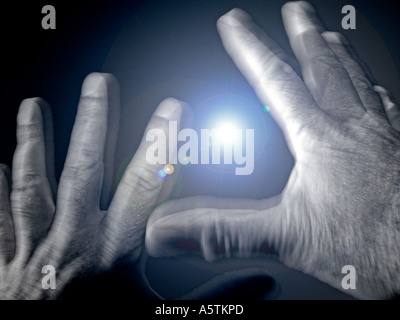 Close up of male hands in act of fear or surrender at night caught in torch light Stock Photo