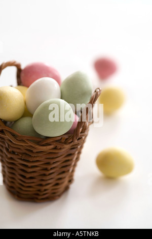 Easter eggs basket with colorful marzipan sweets on white background Stock Photo