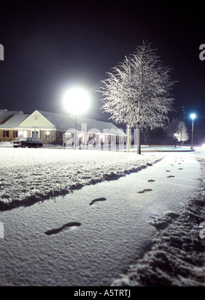 Foot Prints In Snow Sidewalk Path At Night With Lamp Light And Icy Tree, Apartment Complex, Philadelphia Pennsylvania USA Stock Photo