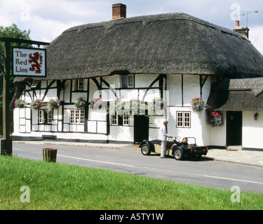 Man helping woman out of sports car in front of the old,thatched, Red Lion Pub,Chalton hampshire,U.K. Stock Photo