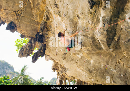 Man climbing overhanging limestone rock face on Tonsai Beach Southern Thailand Stock Photo