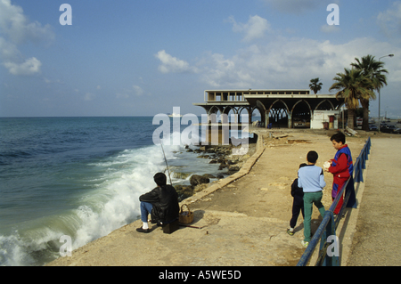 Minet El Hosn District, off Corniche Ave, Beirut, Lebanon - A Man Is Fishing While Kids Are Playing Around Him Stock Photo